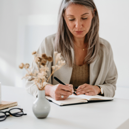 Entrepreneur writing podcast strategy notes in a journal at a desk, planning how to measure if a podcast is working for business growth.