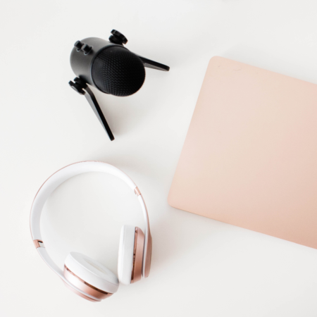Podcast microphone and headphones with notebook for writing episode descriptions that increase downloads
