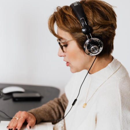Woman recording podcast episode with headphones at home studio workspace