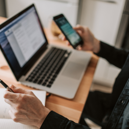 Podcaster optimizing old podcast episodes on laptop and phone to increase podcast downloads using strategic podcast SEO